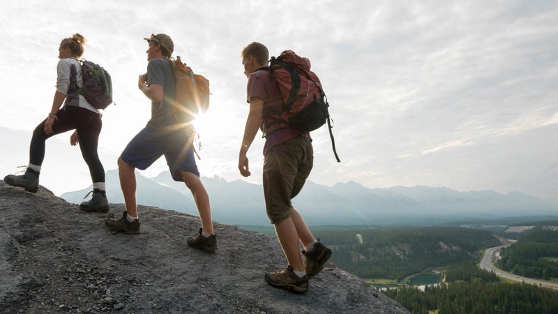 Hikers climb ridge above sunrise, valley