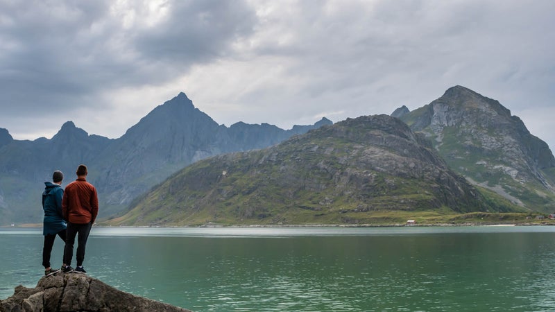 Couple looking at mountain range and fjord of Norway.