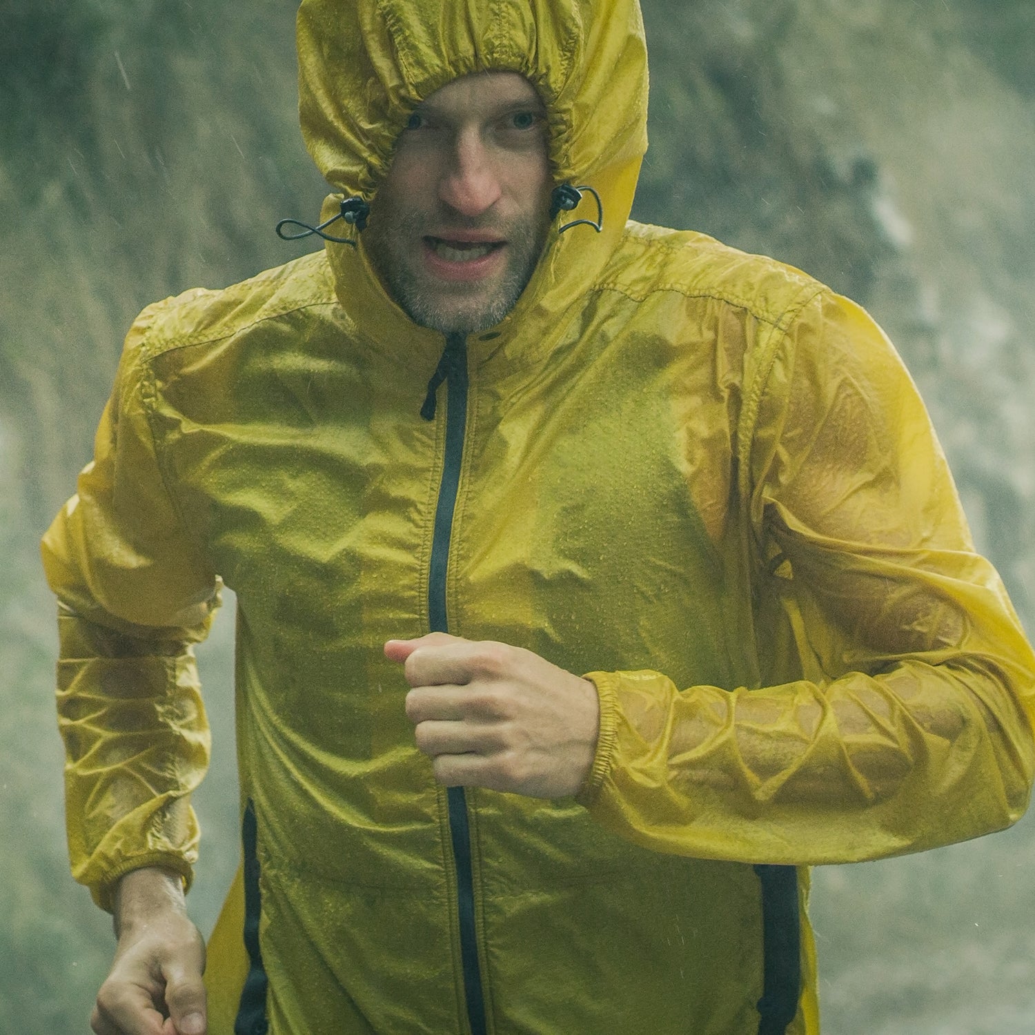 Athletic man jogging in extreme weather condition. Hail and rain