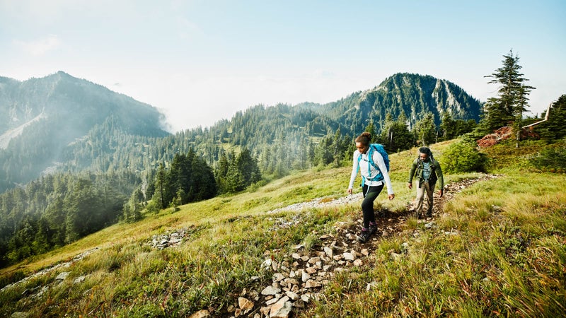 Daughter leading father on morning hike up mountainside