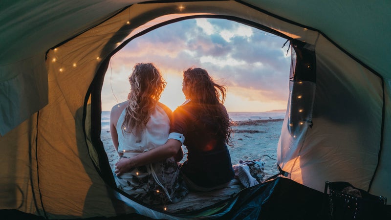 Young adult couple admiring the sunset in a tent on the beach