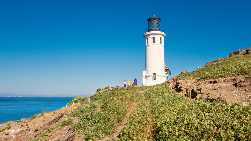 People hike at lighthouse on Anacapa Island in Channel Islands National Park California