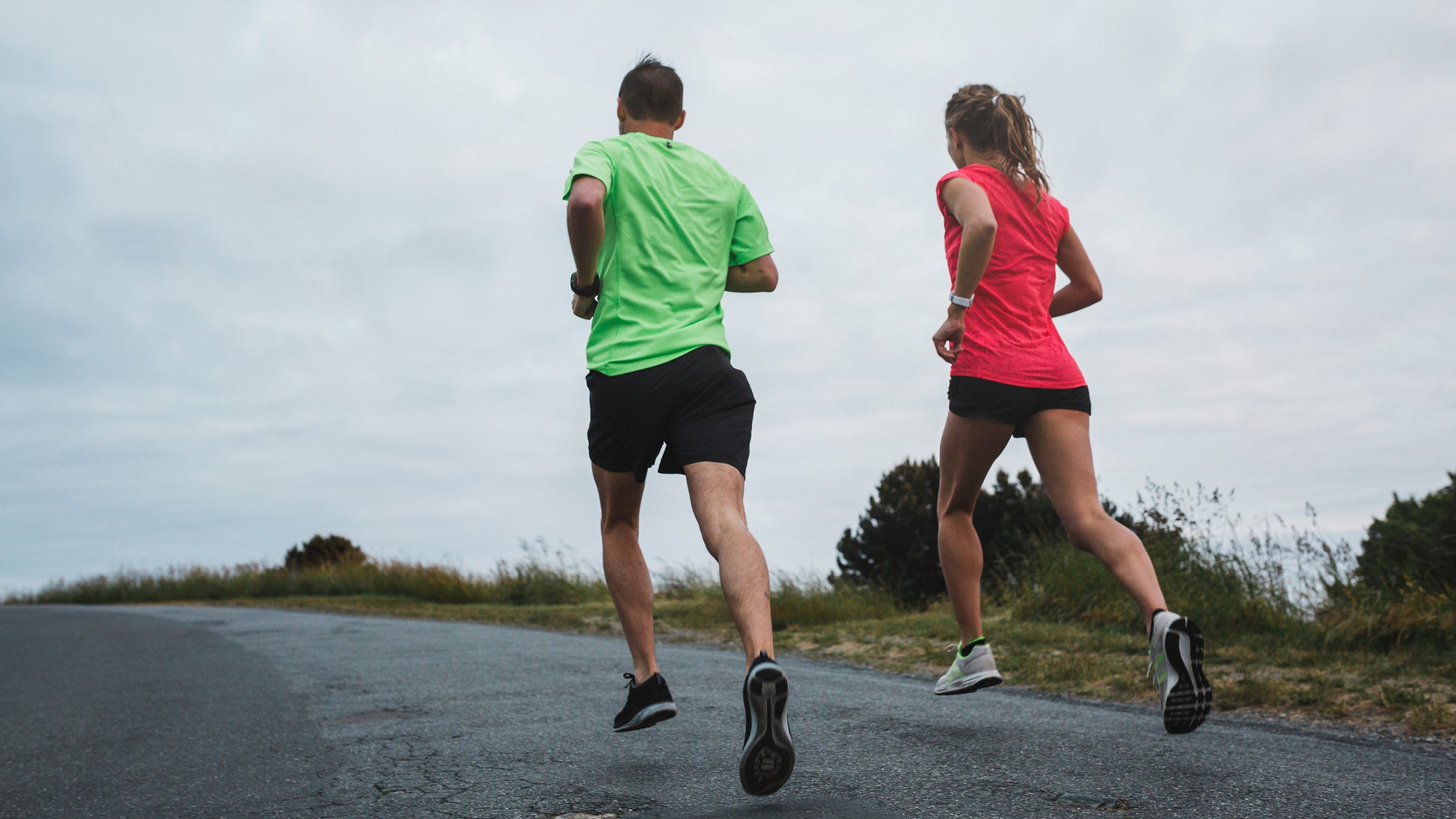 Motivated Young Couple Running Together Outside On Cold, Windy Day
