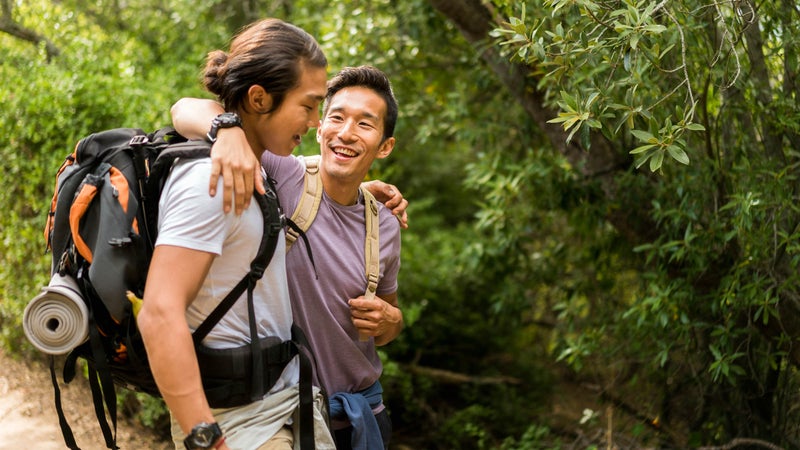Happy friends talking while hiking in forest