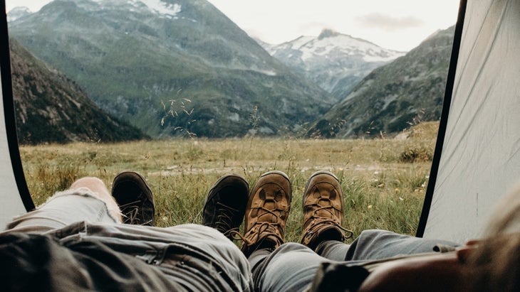 Two people lying down in a tent facing a view of the mountains