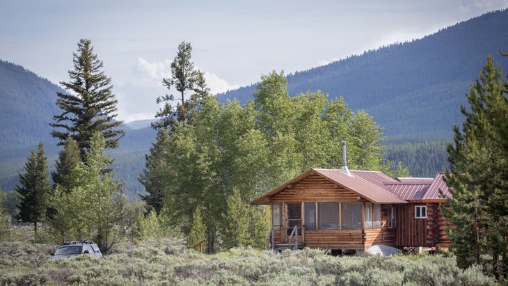 The cabin, with new additions, surrounded by regrowing forest and backed by the thickly forested Whitefish Range.