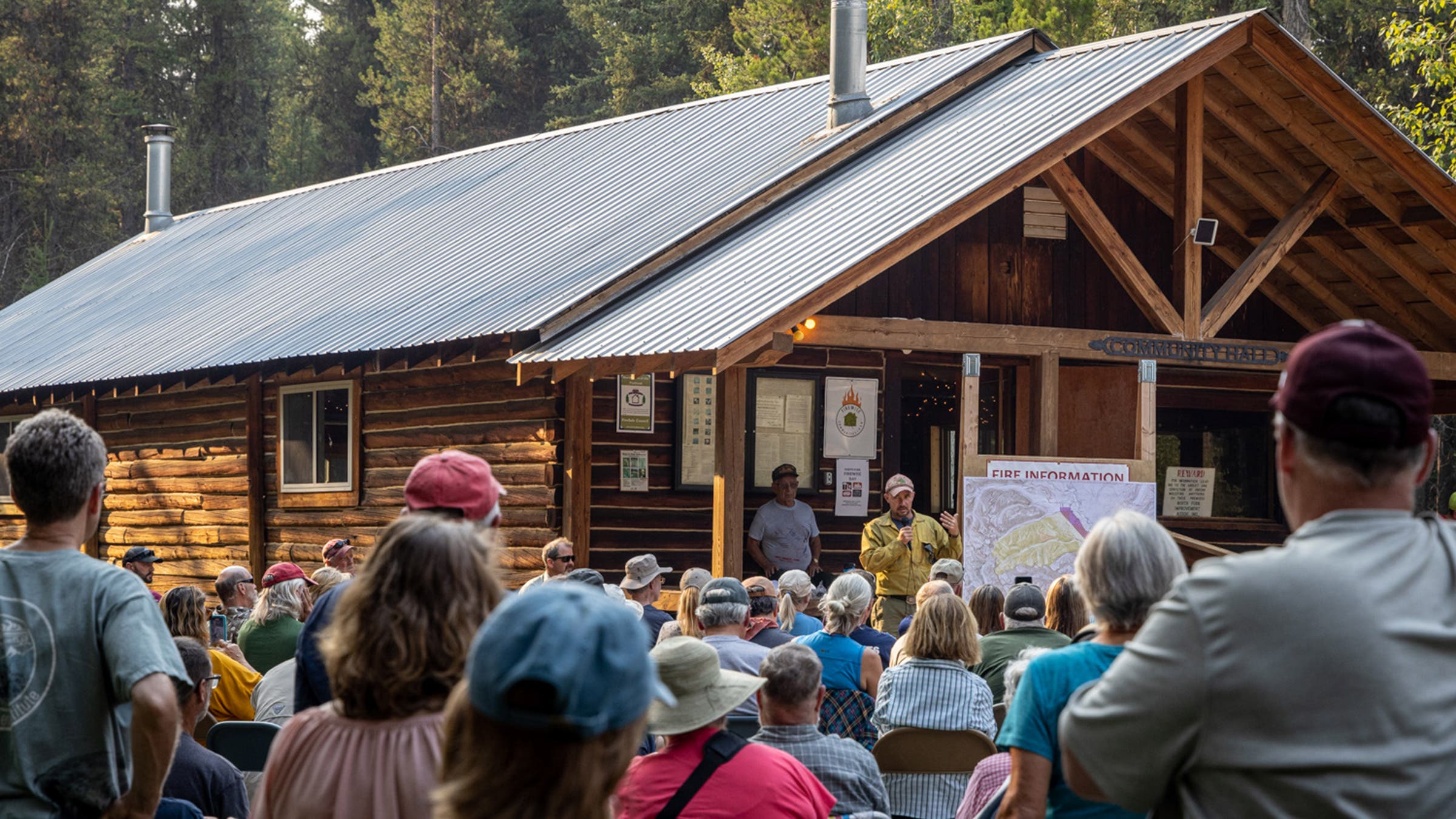 Fire crew leaders, including Mike West with mic, speak at public meeting in the remote valley's community center.
