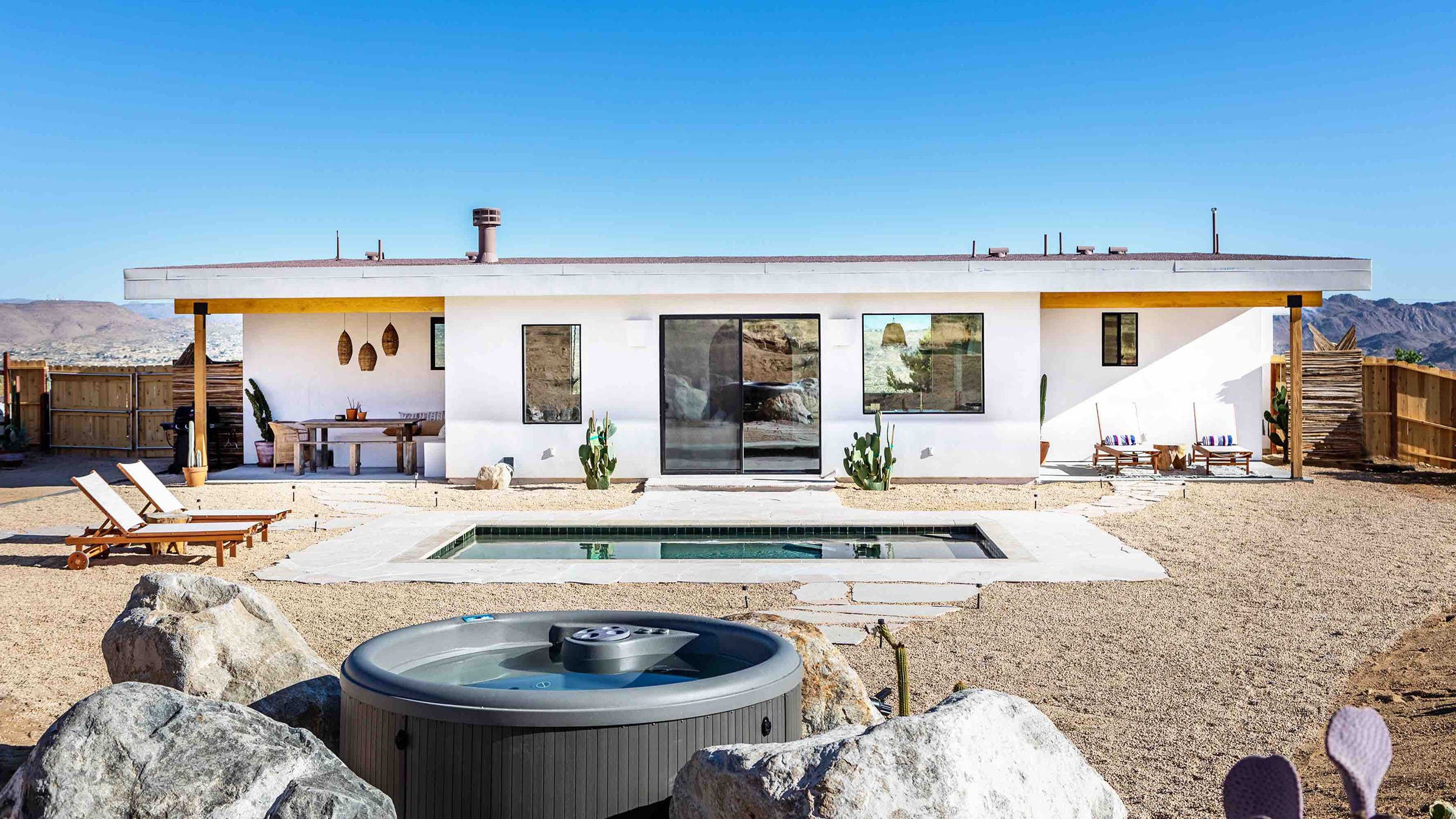 white desert home with small pool and hot tub in backyard