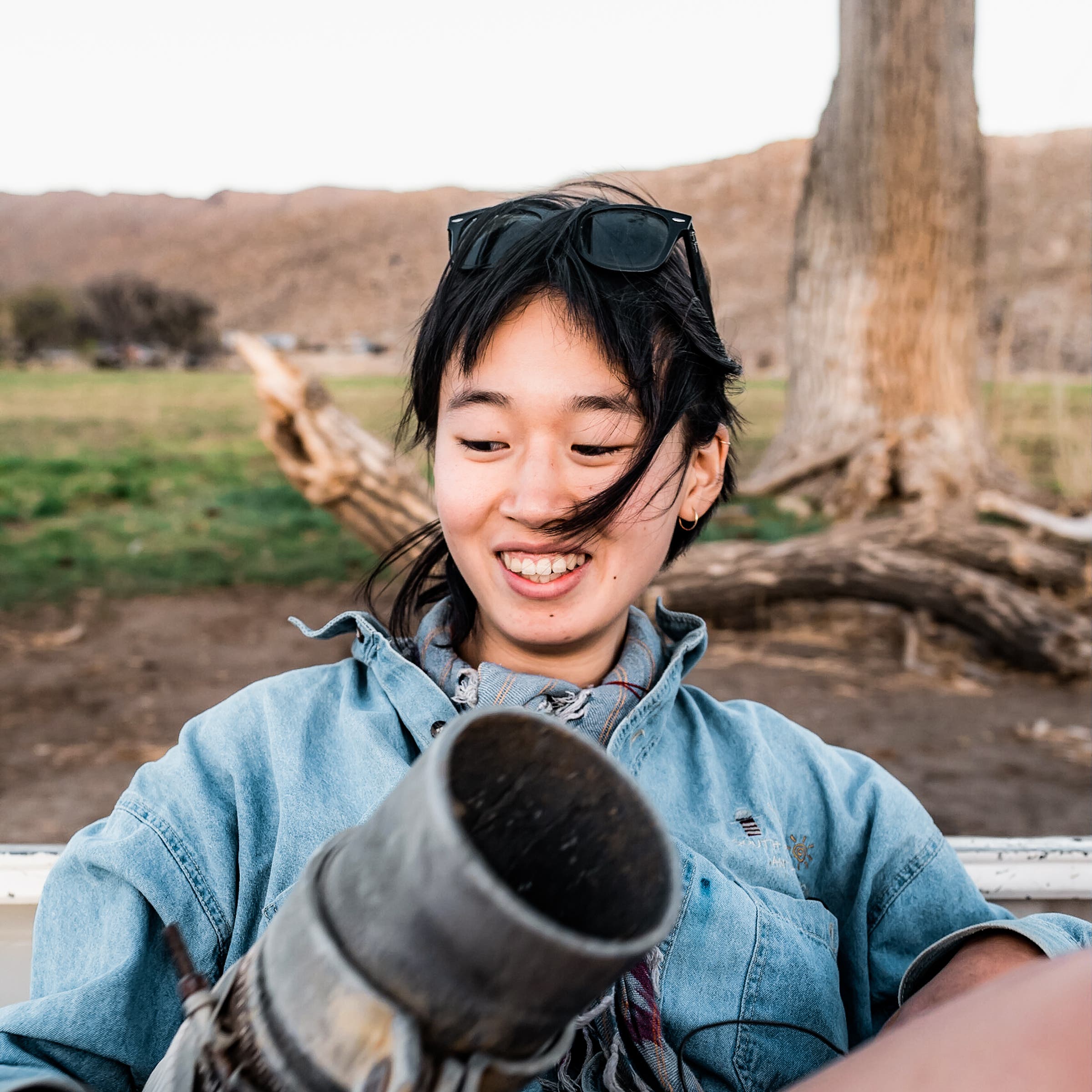 Connie Jiang riding in the farm truck in 2021, holding an irrigation hose