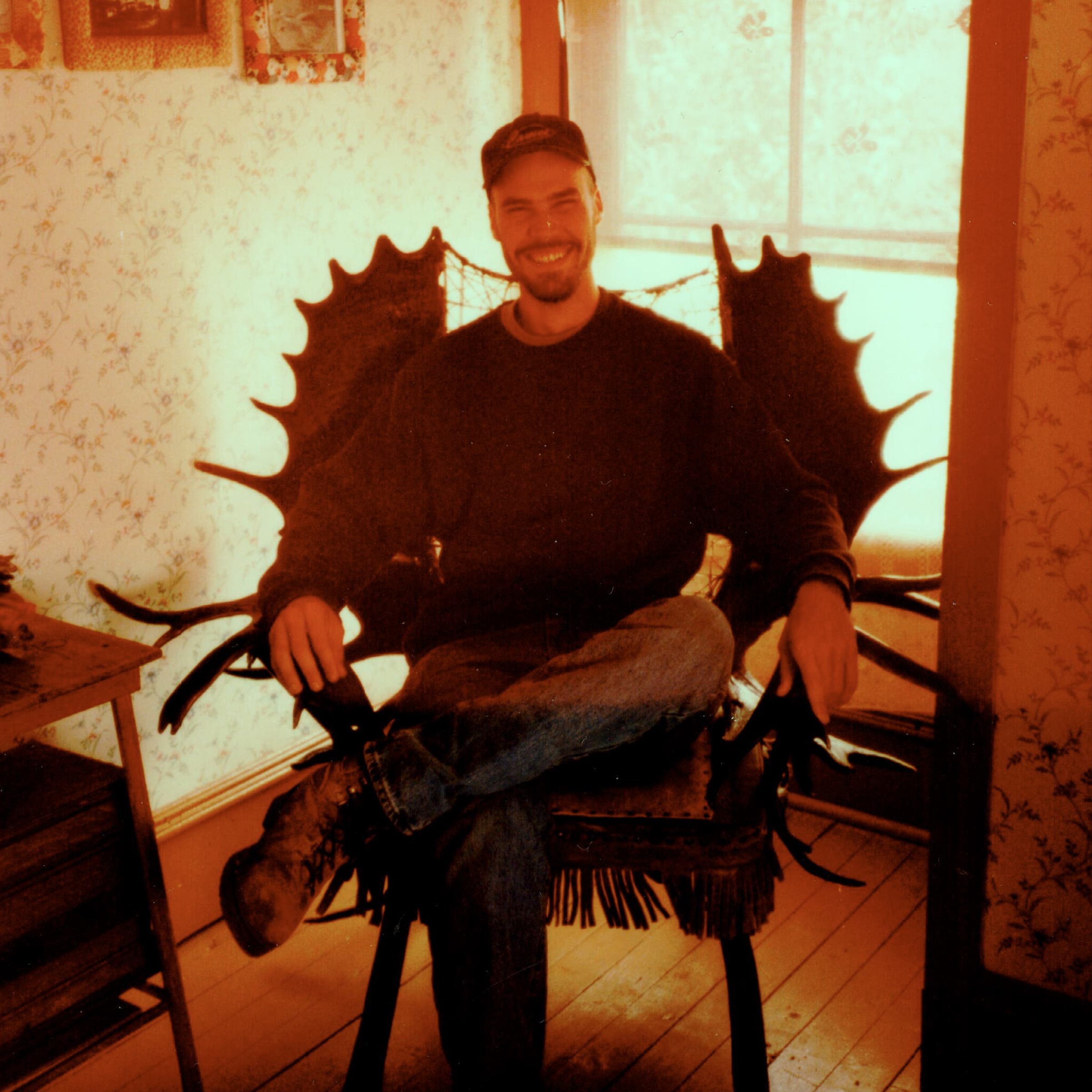 Genoways sitting in a chair made of moose antlers in the history museum in Eagle, Alaska