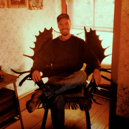 Genoways sitting in a chair made of moose antlers in the history museum in Eagle, Alaska