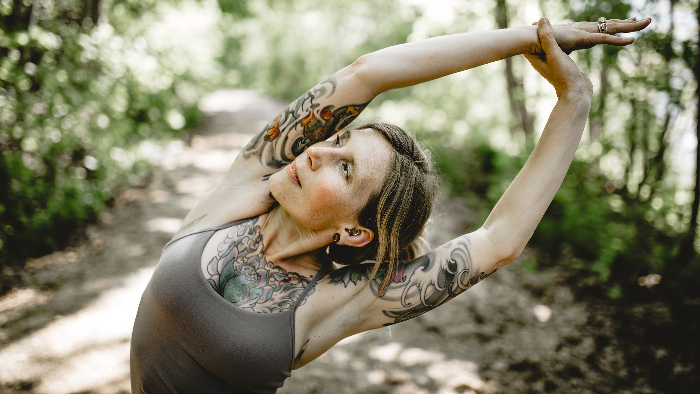 Woman with tattoos stretching in a forest
