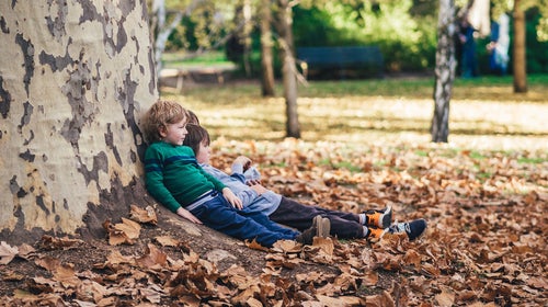 Kids leaning on tree