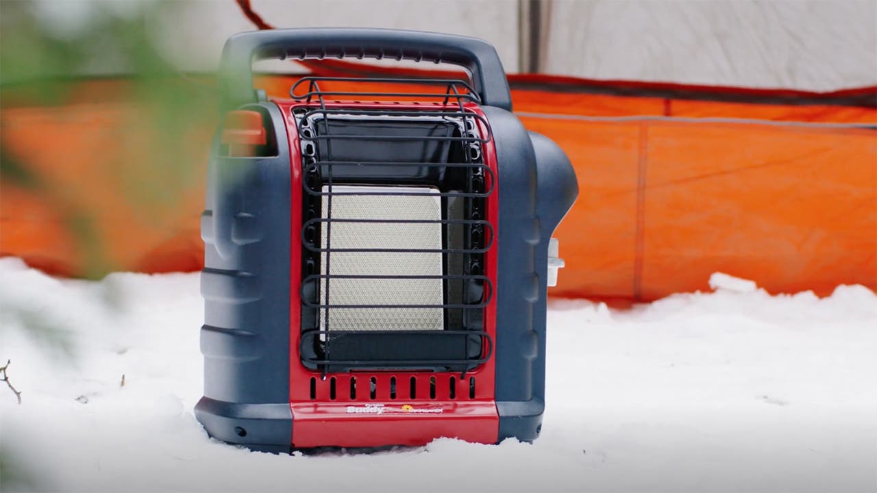red and black propane heater sitting in snow outside tent