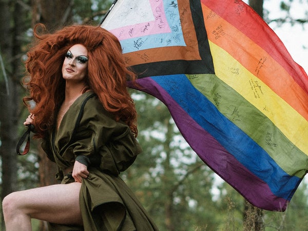 Pattie Gonia poses with a pride flag