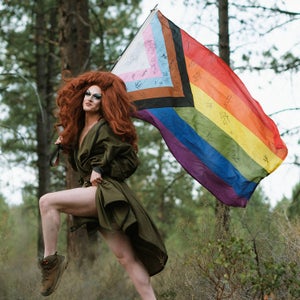 Pattie Gonia poses with a pride flag