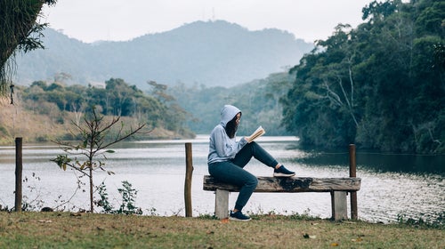Young woman reading a book by the lake
