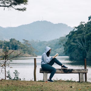 Young woman reading a book by the lake