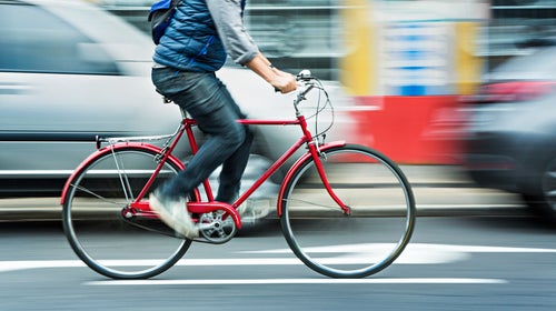 Person cycling on red bicycle in street