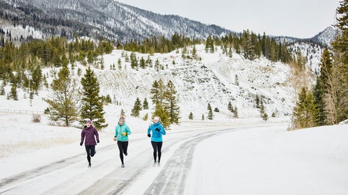 Three friends exercising in the cold on a snowy road