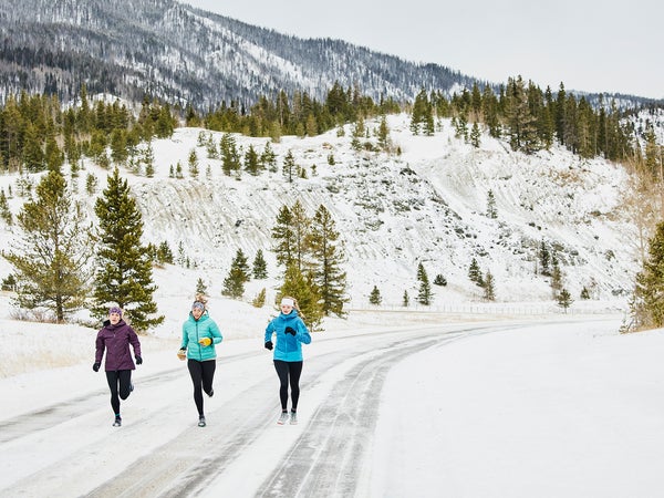 Three friends exercising in the cold on a snowy road
