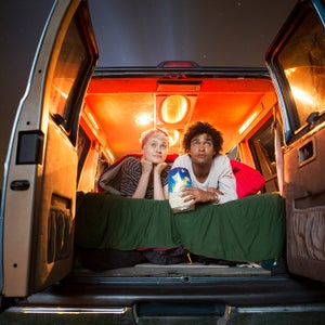 Couple holding popcorn while sitting in camping van during drive-in movie