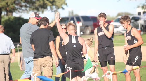 cross country runners hanging out in a group giving a high five to their coach