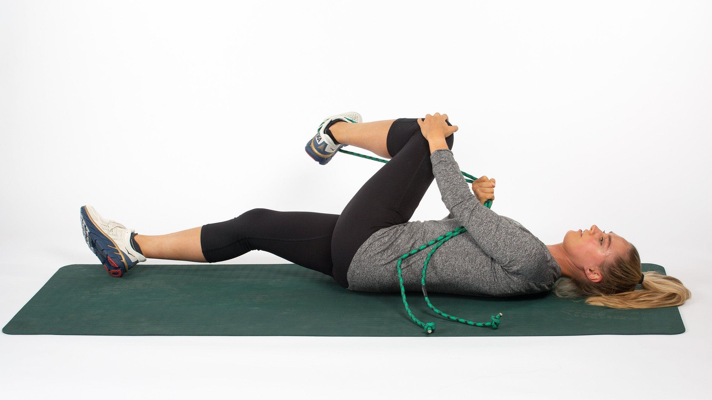 Woman lying on back using rope to stretch gluteals