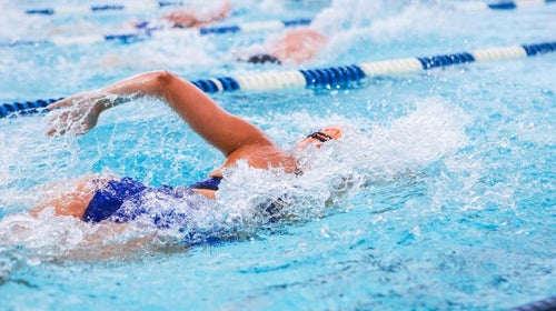 Woman in mid-stroke in pool swim lane