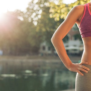 Cropped shot of woman in sportswear standing with her hands on hips outdoors.