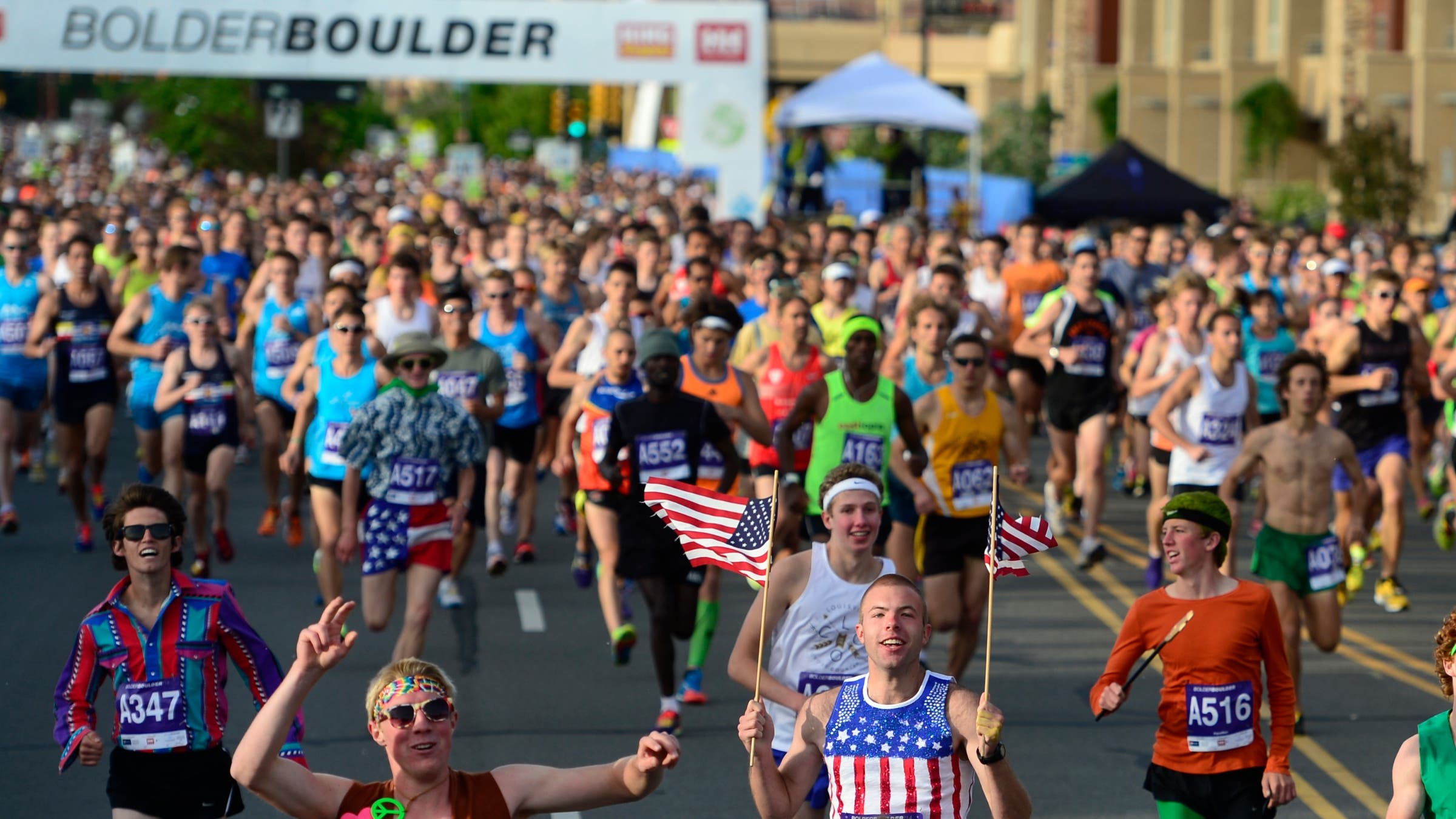 Racers in the BOLDERBoulder 10K wave American flags on Memorial Day.