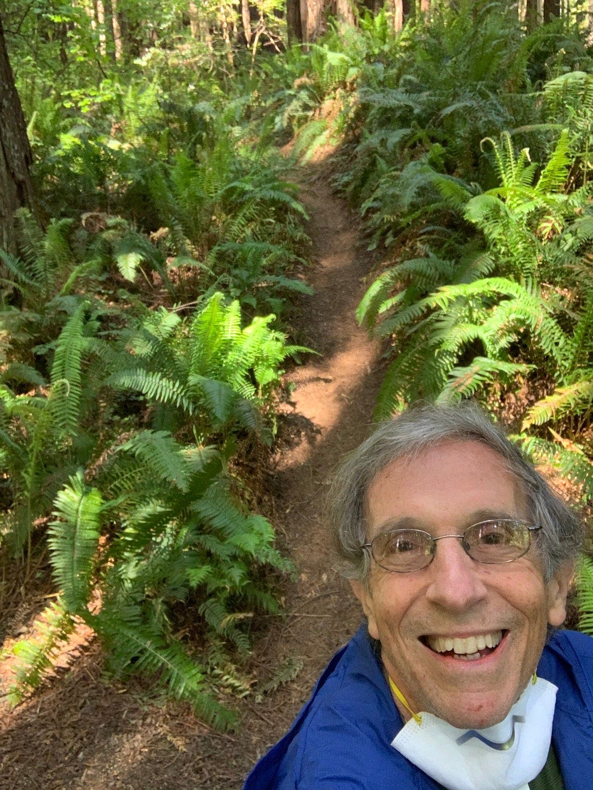 Man taking a selfie on trail with COVID-19 mask pulled down.