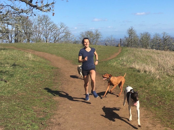 Athlete running in the Saucony Freedom 4 shoe on dirt path with her dogs.