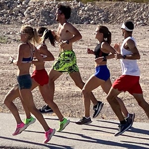 Group of runners training in hot weather on road.