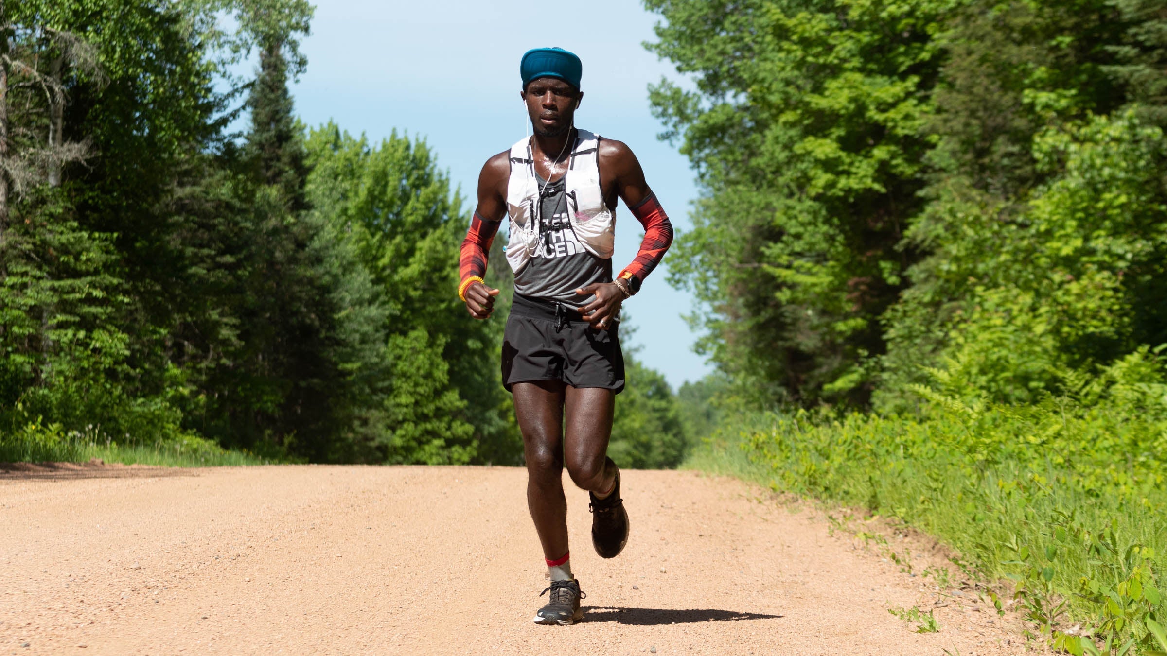 Coree Woltering running along a dirt road on a sunny day