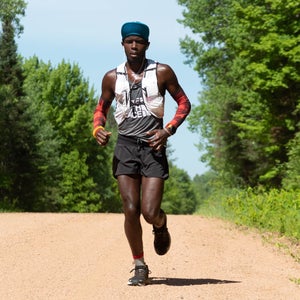 Coree Woltering running along a dirt road on a sunny day