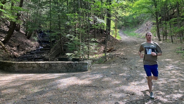 Man running downhill in woods on running streak.