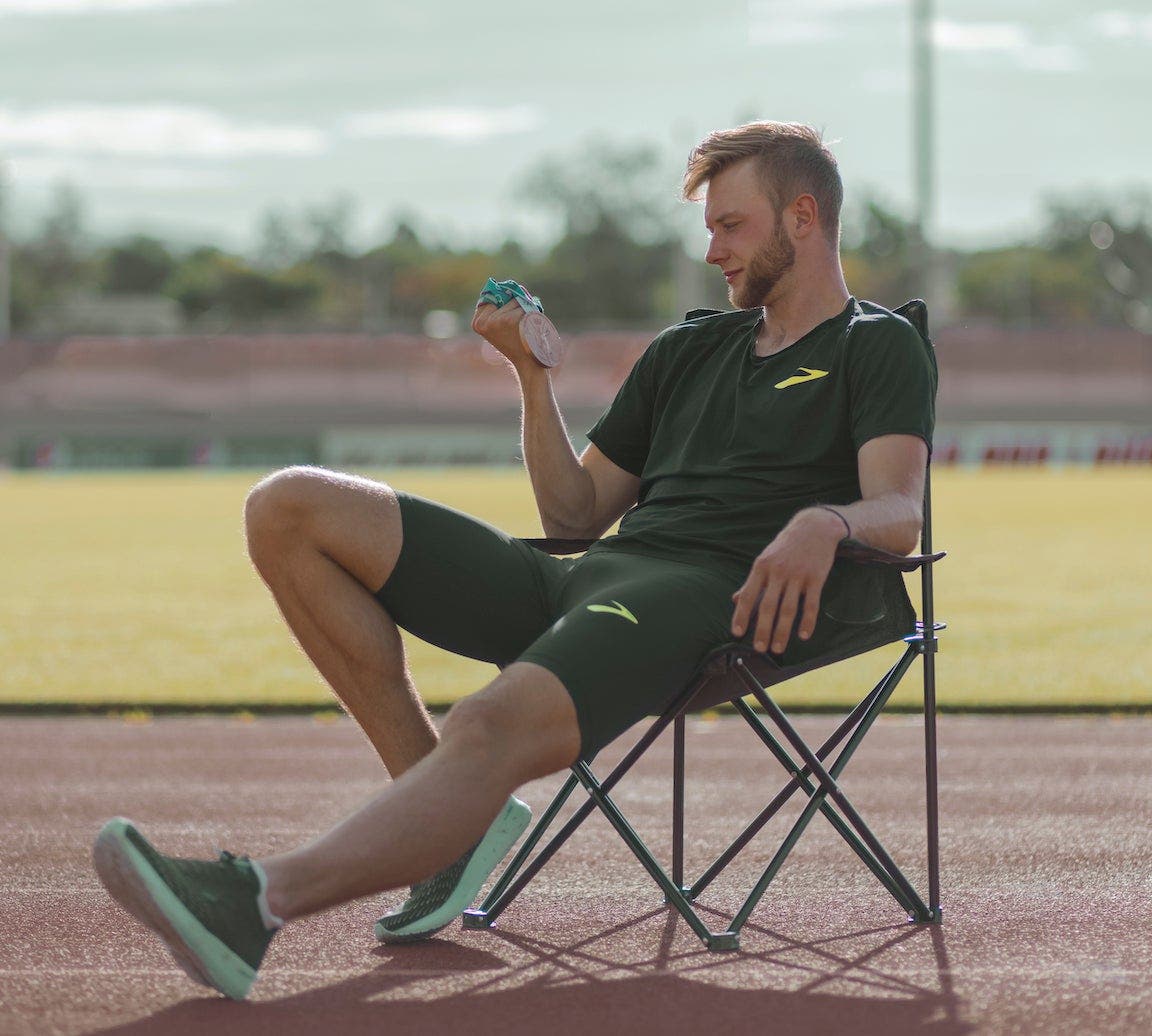 Josh Kerr in lawn chair on track looking down at his bronze medal.