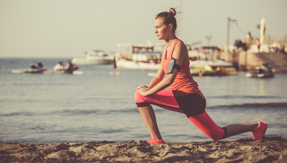 Copy space shot of a young woman doing stretching exercises by the sea.