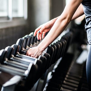 Young woman choosing dumbbell at a gym