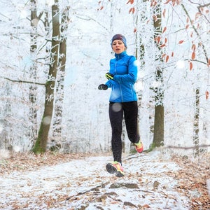 A young woman jogging in the wintry forest.