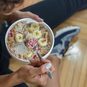 Young woman eating a oatmeal after a workout. Oats are good cross country nutrition.