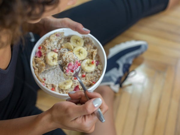 Young woman eating a oatmeal after a workout. Oats are good cross country nutrition.