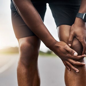 Closeup shot of a sporty man suffering with knee pain while exercising outdoors.