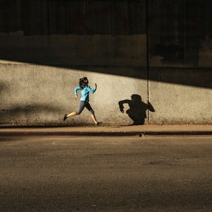 Woman running against wall on city street