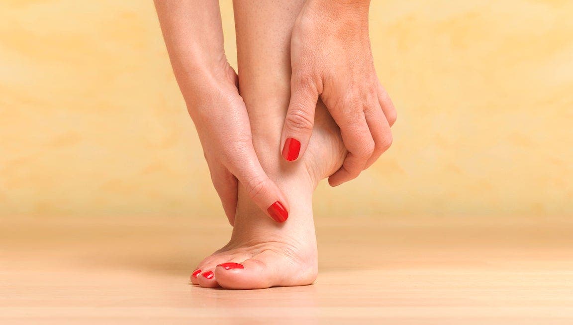 woman removed shoes to massage painful foot.