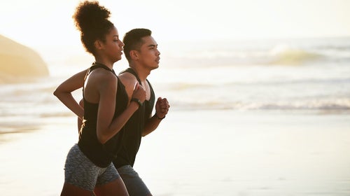 Shot of a young couple running many miles along the beach.