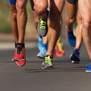Marathon runners' legs running race on city roads.