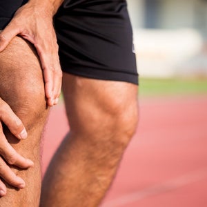 Man touching sore knee on a track.