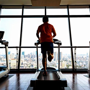 Man running on treadmill overlooking city.